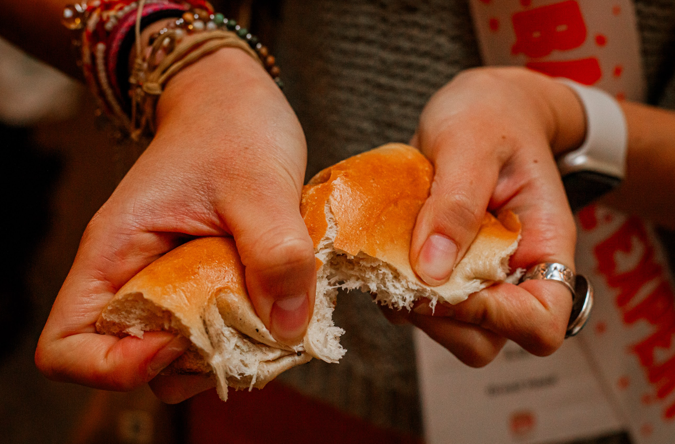 Hands pulling apart a fresh soft bagel showing fluffy interior texture at BagelFest West Los Angeles
