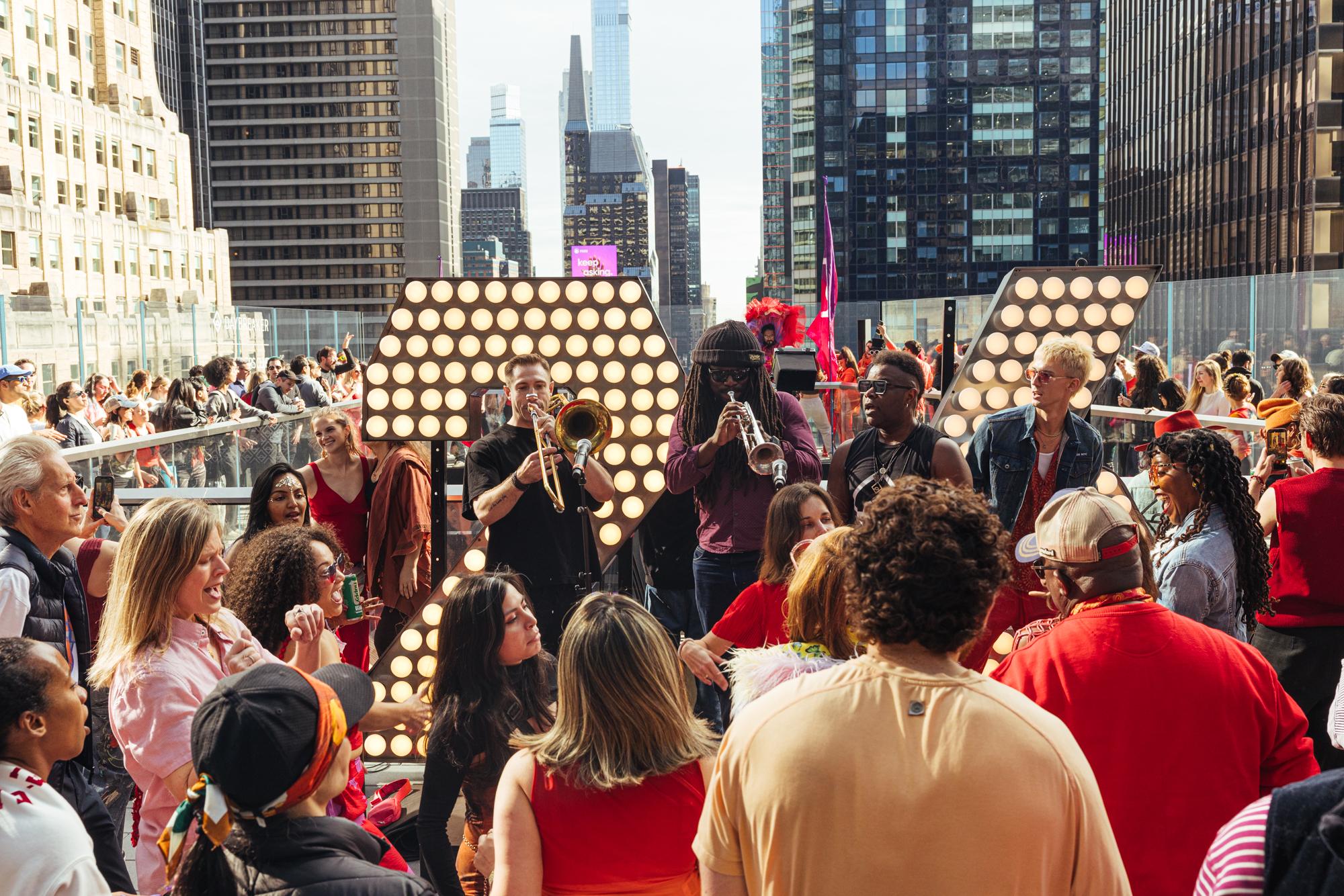Hundreds of Daybreaker participants dancing at sunrise atop One Times Square overlooking the Manhattan skyline.