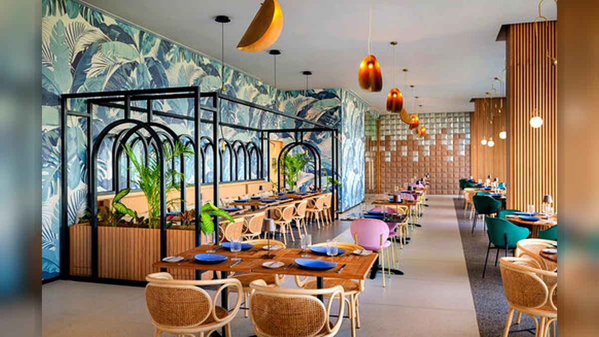 Dining area inside Mondrian Cancun with tropical wall art, rattan chairs, colorful seating, and modern pendant lights.